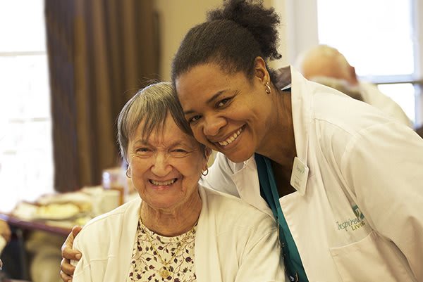 A nurse smiling alongside an elderly woman, showcasing companionship and care in a healthcare setting.