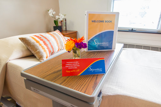 A welcoming hospital patient room setup featuring a table adorned with flowers and informational materials.