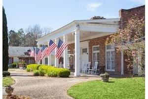 A brick house with a large front porch adorned with multiple American flags.