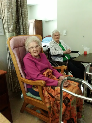 Two elderly women enjoying each other's company in a care facility.