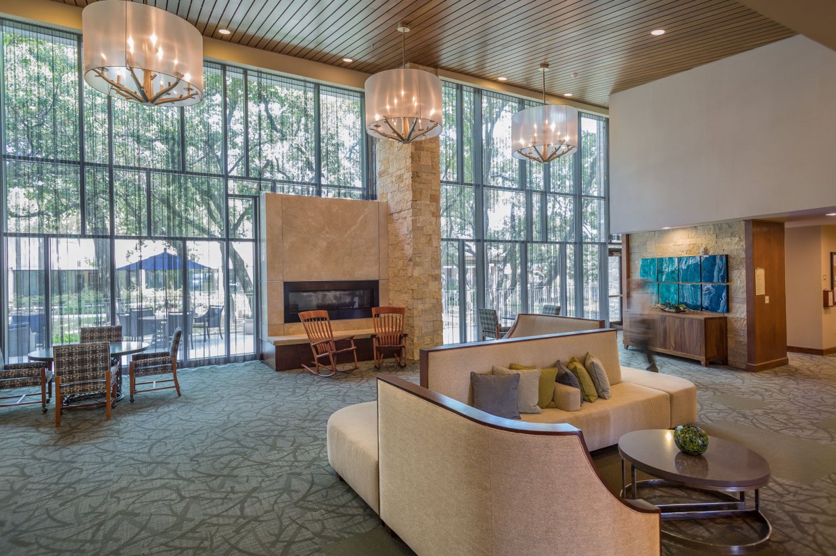 A modern lobby with comfortable seating, a fireplace, and large windows.