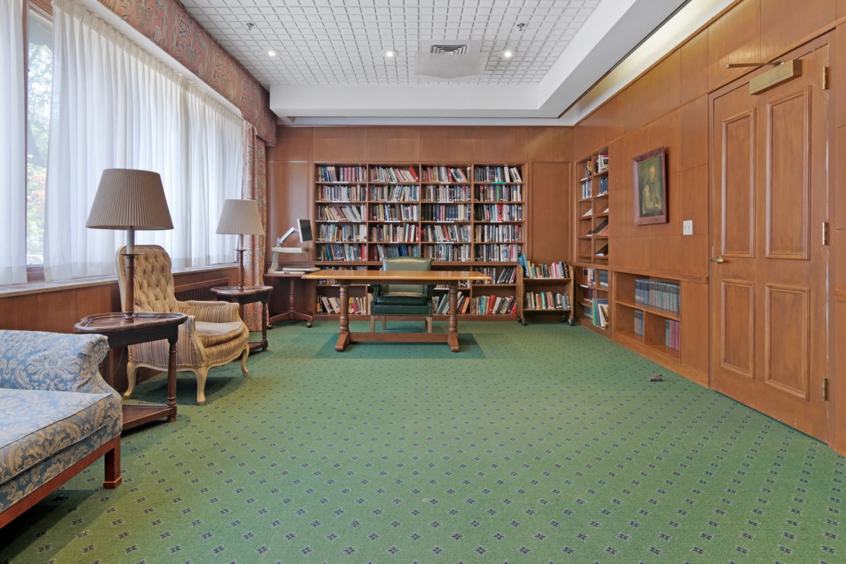 A cozy library room with bookshelves, a desk, and comfortable seating.