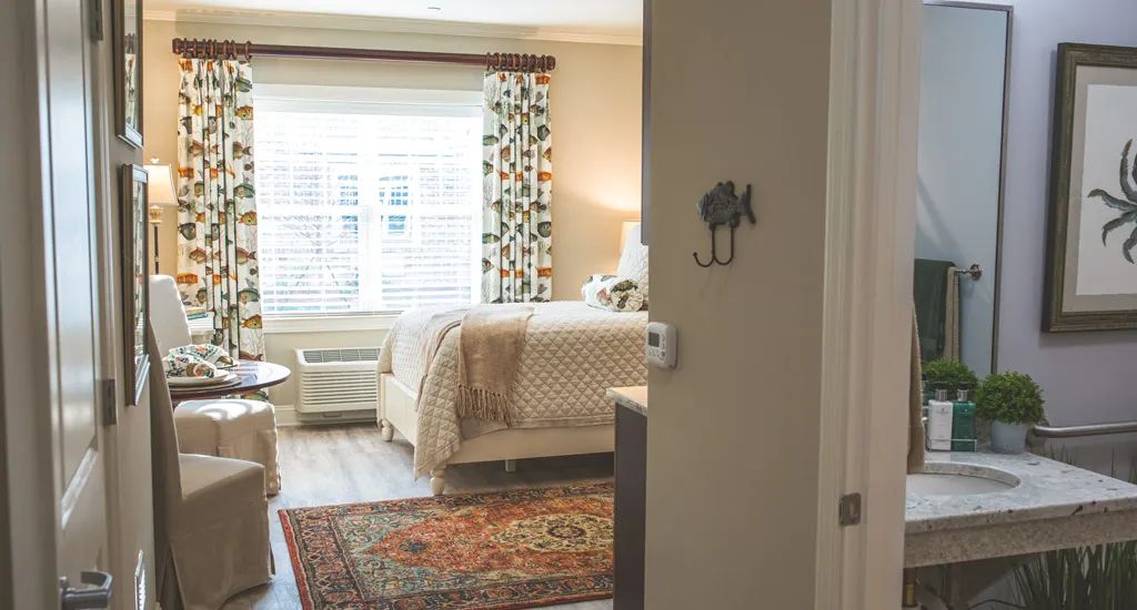 A cozy bedroom with a patterned rug, curtains, and soft lighting.