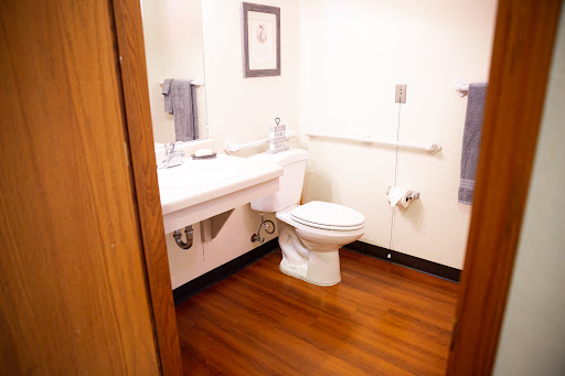 A clean and accessible bathroom featuring a toilet, sink, and handrails.