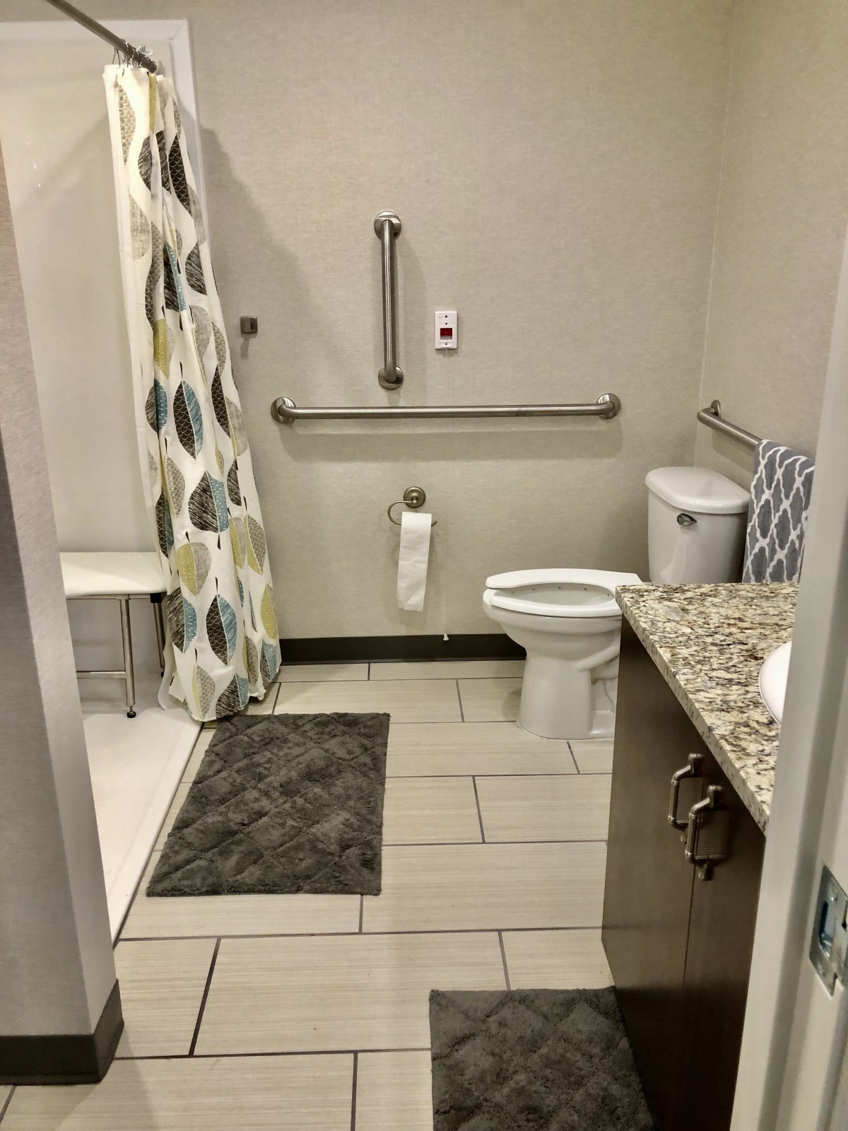 An accessible bathroom with a shower, grab bars, and tiled flooring.