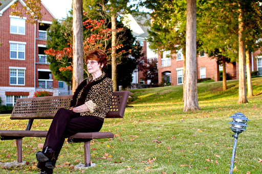 A woman sitting on a bench in a park surrounded by trees and the vibrant colors of autumn.