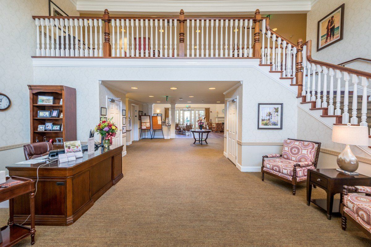 A spacious lobby area featuring a staircase, comfortable seating, and decorative furnishings.