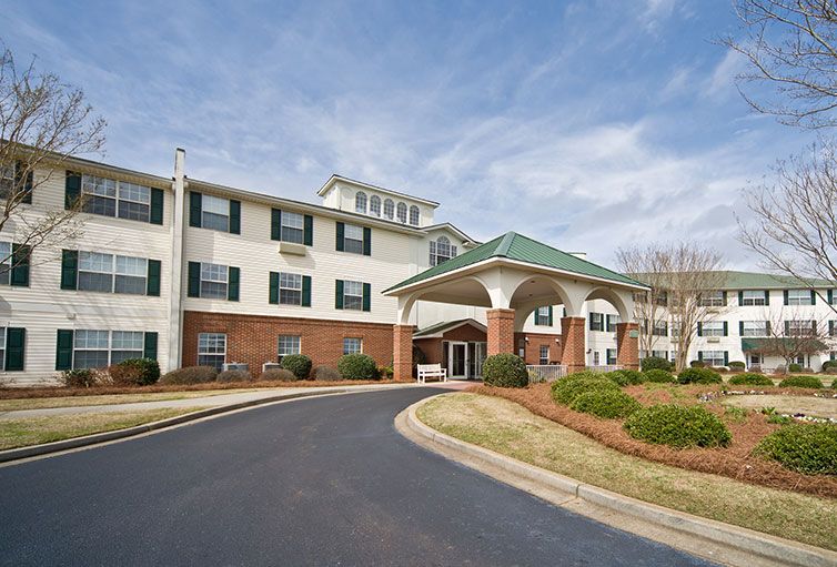 A three-story hotel building with a grand entrance and landscaped surroundings.
