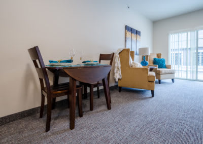 A cozy living room and dining area featuring a wooden table, chairs, and comfortable seating with a bright and open feel.