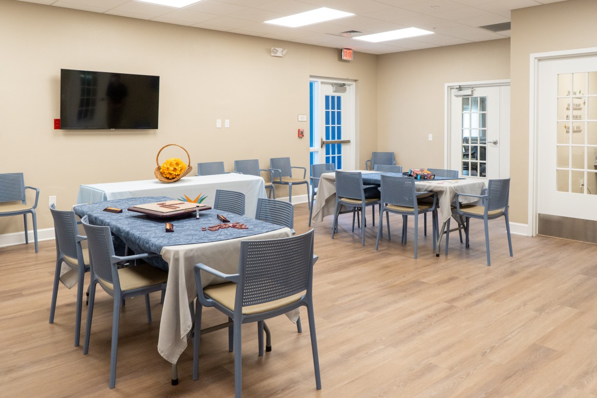 A modern dining area with arranged tables and chairs, featuring a wall-mounted television.