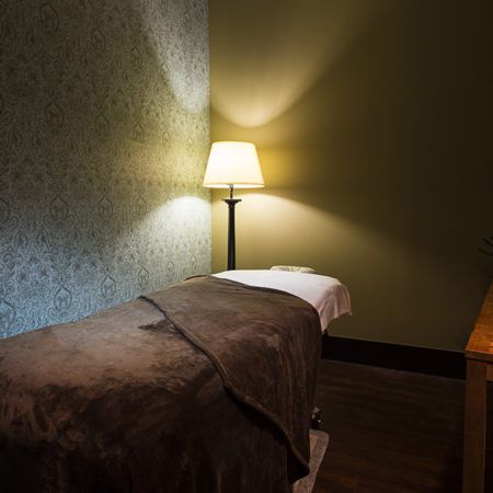 A serene massage room with a cozy bed and soft lighting, perfect for relaxation.