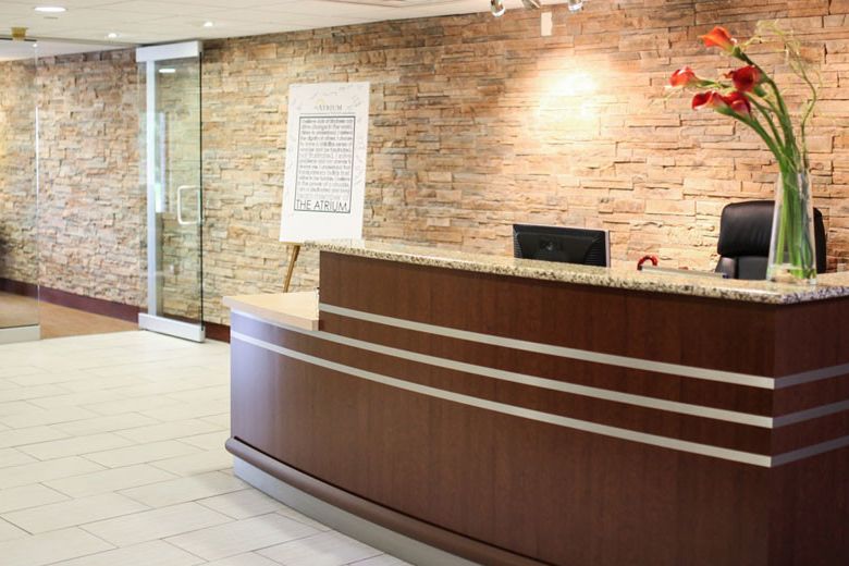 A modern office lobby with a wooden reception desk and a brick accent wall.