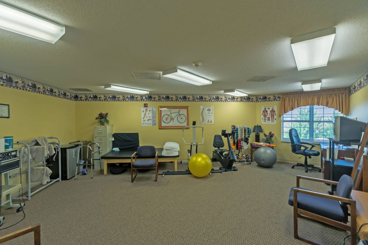 A spacious exercise room equipped with various fitness and therapy equipment, including therapy balls and chairs.