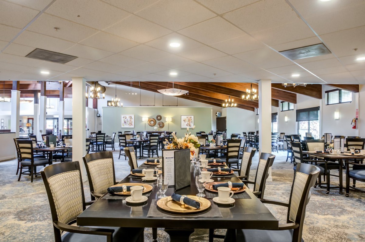 A spacious and elegantly set restaurant dining area with neatly arranged tables and chairs.