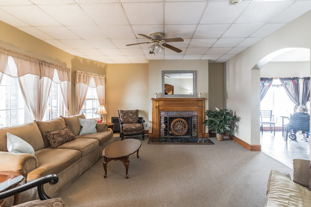 A cozy living room with a fireplace, sofa, and ceiling fan.