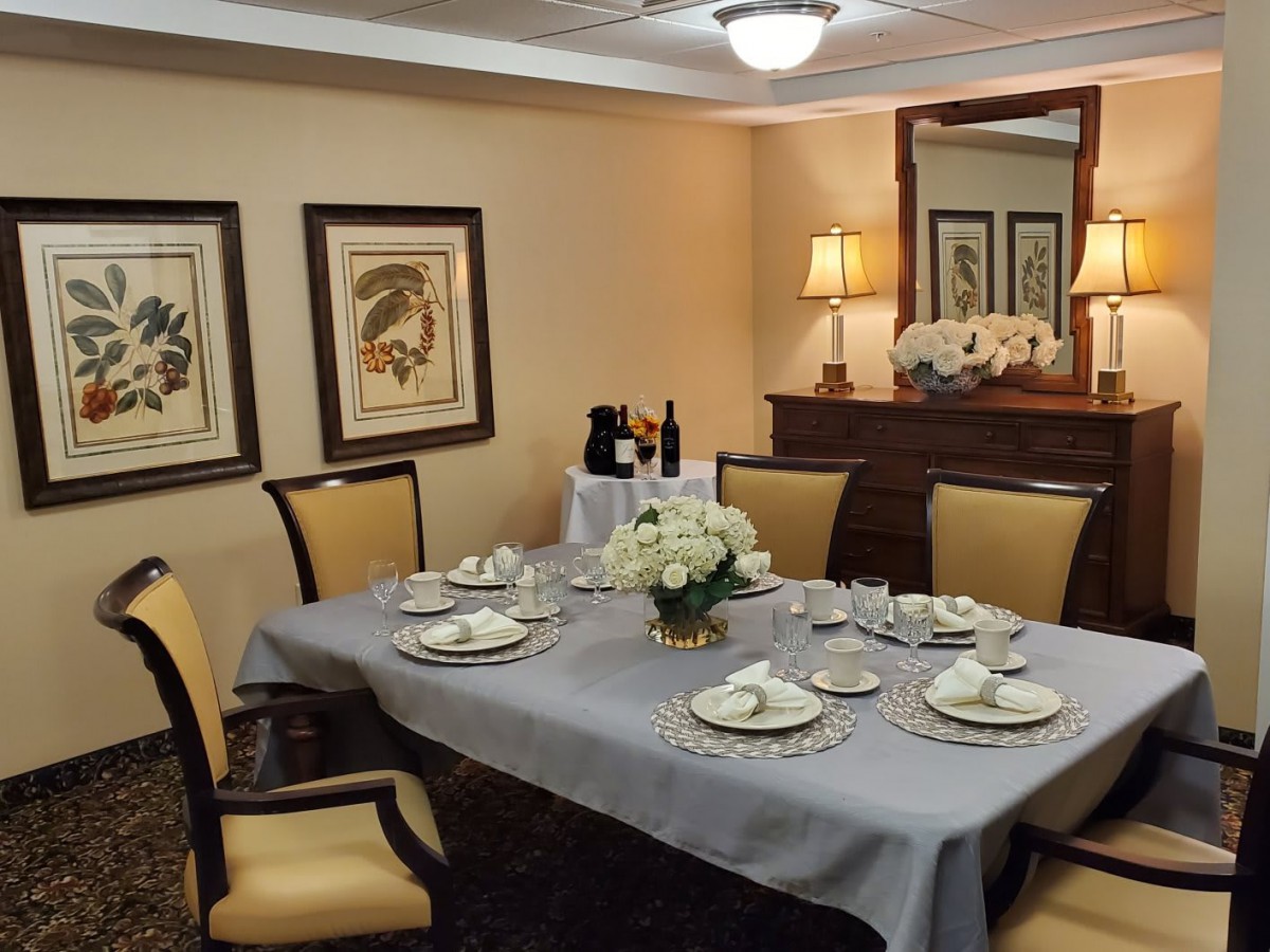 An elegantly set dining room table with fine dinnerware and a centerpiece, surrounded by classy decor.