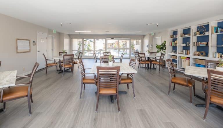 A spacious and bright modern dining room with multiple tables and chairs.
