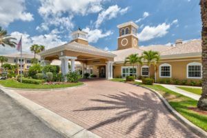 A sunny view of an elegant building entrance surrounded by palm trees.