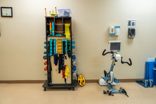 A well-equipped rehabilitation room featuring various weights and a stationary exercise bike.