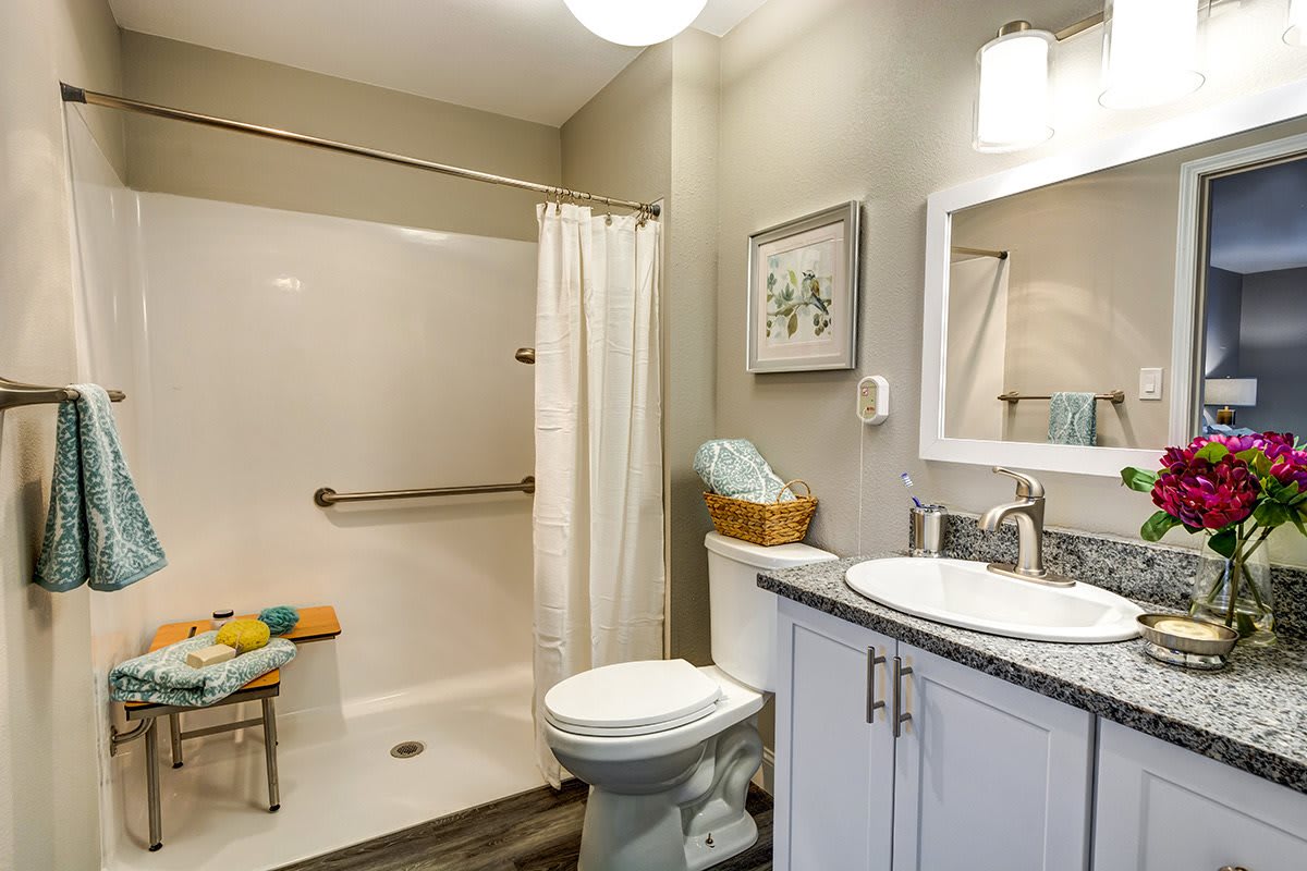 A modern bathroom featuring a shower with a curtain, toilet, and sink with a mirror.