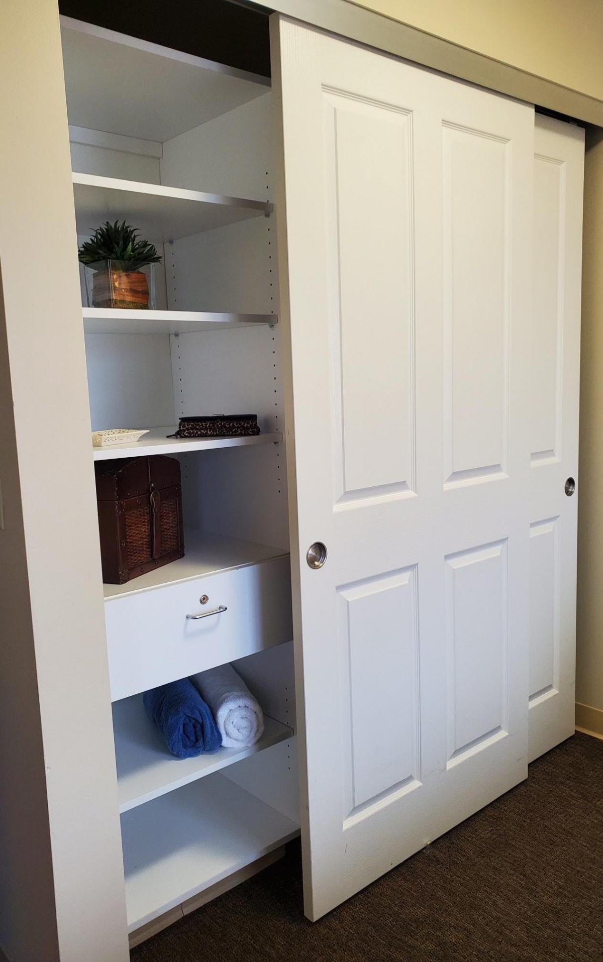 A neatly organized closet with shelves and a sliding door.
