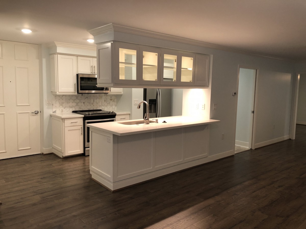 A modern kitchen with a central island and white cabinetry.