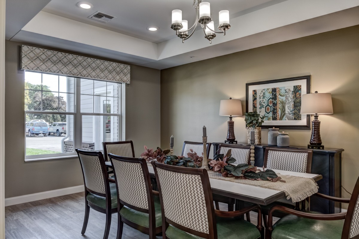 A neatly arranged dining room with a table set for dinner, featuring elegant chairs and a stylish chandelier.