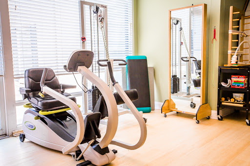 A modern rehabilitation gym featuring specialized exercise equipment and a mirror.