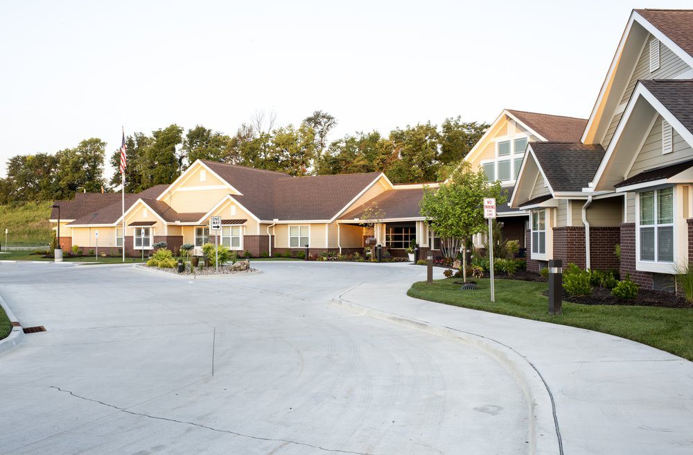 A nursing home building with a driveway and surrounding greenery.