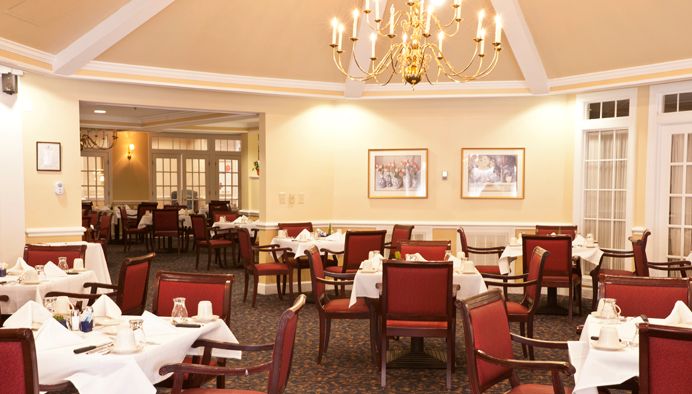 An elegant dining room with neatly arranged tables and a chandelier.