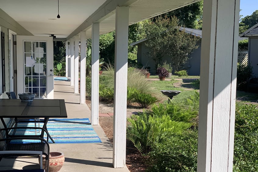 A view of a porch with white columns overlooking a garden.