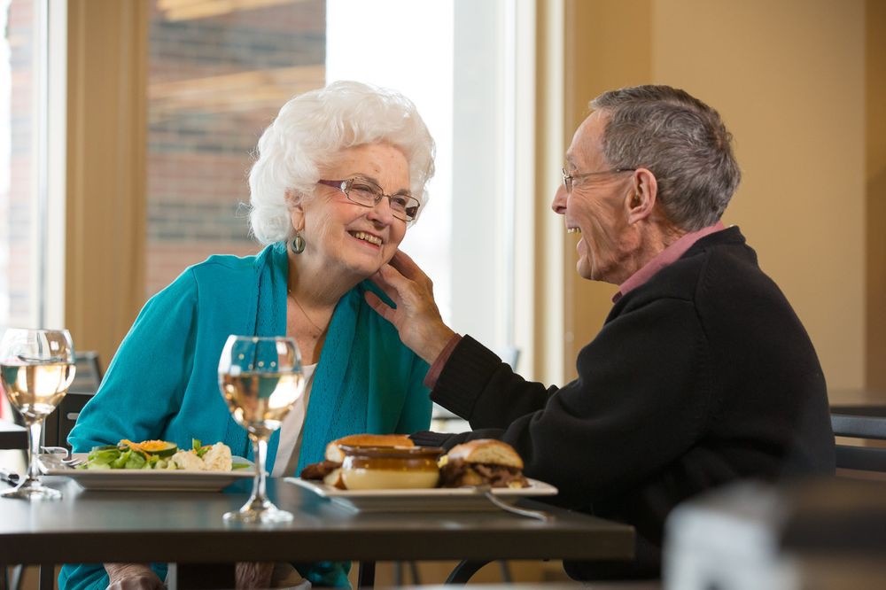 An elderly couple sharing a tender moment while dining together in a restaurant.