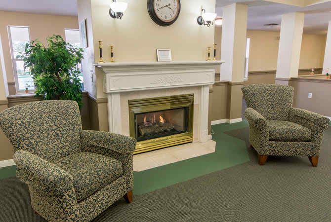 A cozy living room with two armchairs and a fireplace.