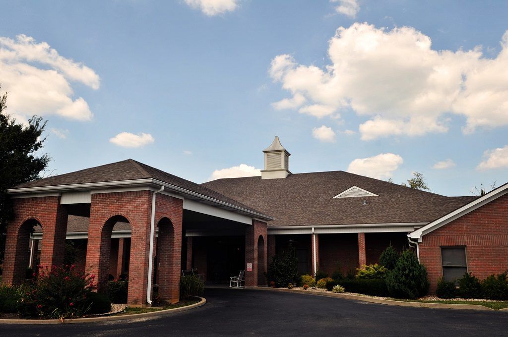 A brick building with a covered entrance under a partly cloudy sky.