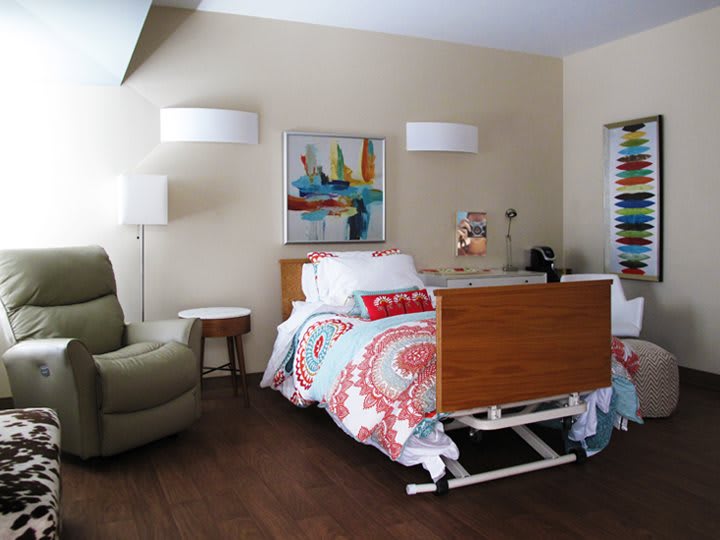 A cozy, well-decorated room featuring a hospital bed, comfortable chair, and stylish decor.