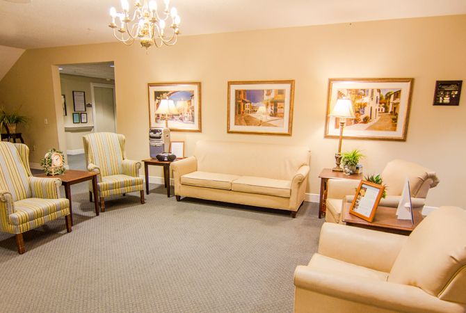 A cozy living room featuring beige sofas, wall art, and a chandelier.