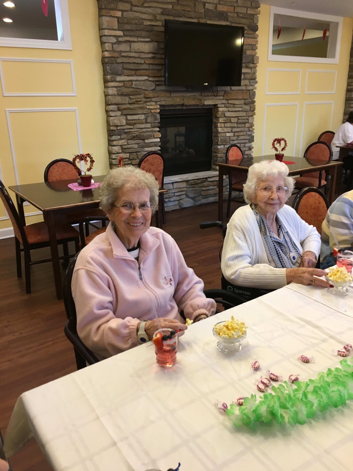 Two elderly women seated at a decorated table during a social gathering.