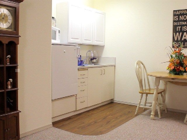 A compact kitchenette with a dining area, featuring cabinets and a small table with chairs.