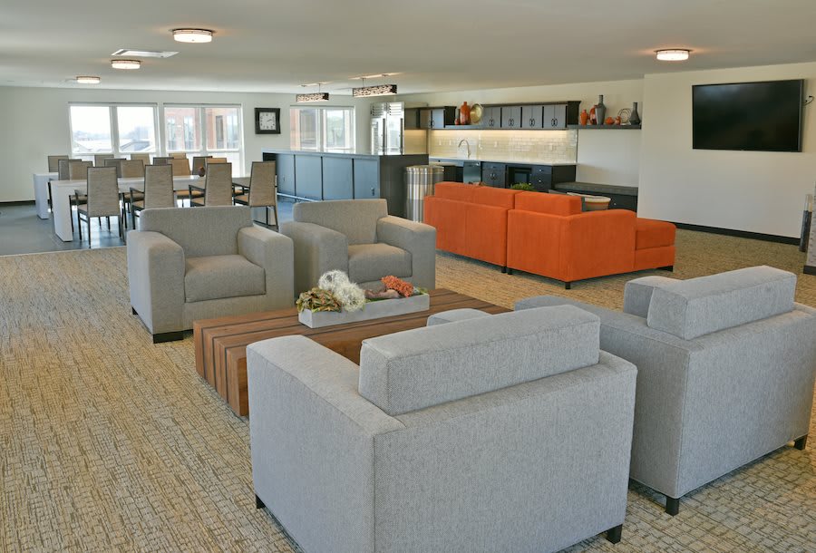 A modern living room with gray armchairs, an orange sofa, and a wooden coffee table.