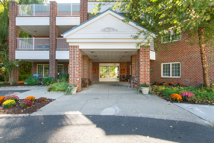 A brick building entrance with a canopy and landscaped pathway.
