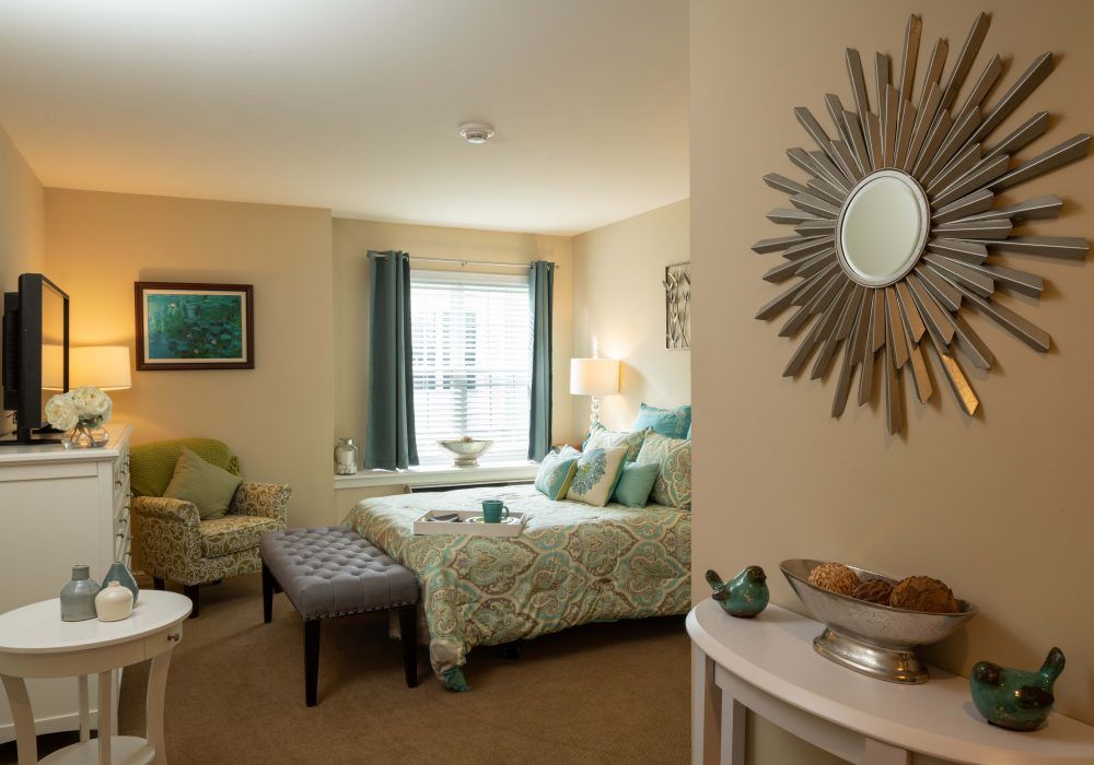 A cozy bedroom with tasteful decor, featuring a bed, chair, and stylish mirror.