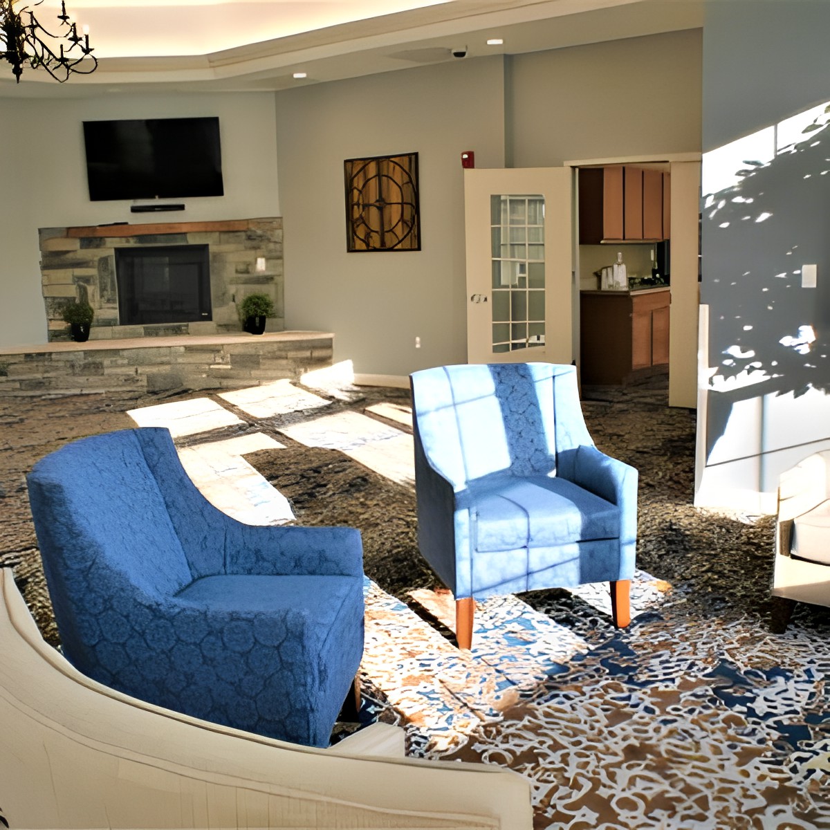 A modern living room featuring blue chairs, a fireplace, and ample natural light.