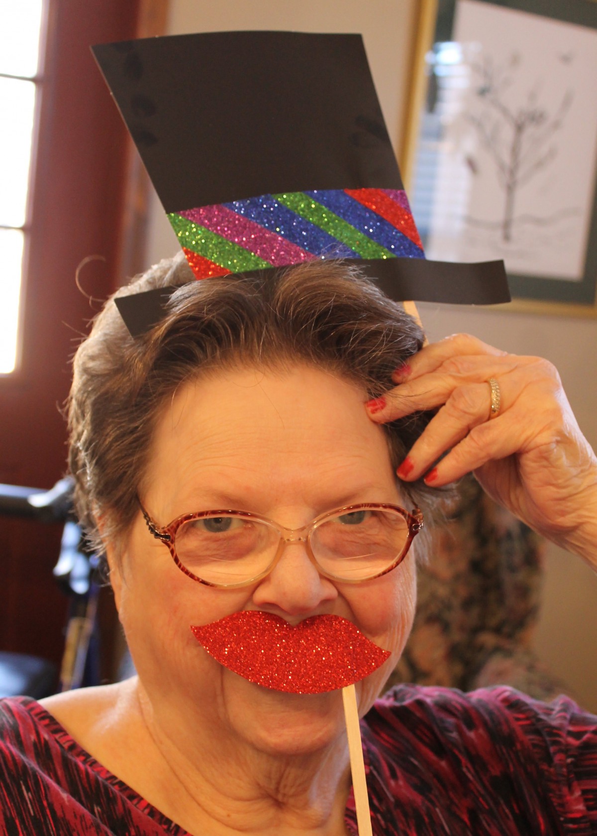 A person having fun with a colorful top hat and fake mustache.