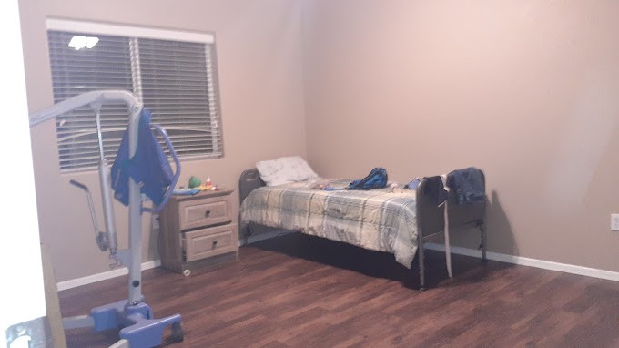 A minimalist bedroom with a single bed, nightstand, and wooden flooring.