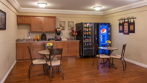 A cozy breakroom featuring a vending machine with Pepsi and snacks, complemented by tables and chairs for relaxation.