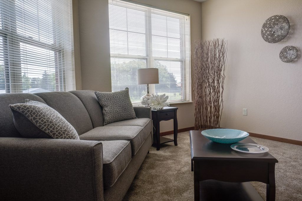 A cozy living room with a grey sofa, side table, and decorative elements.