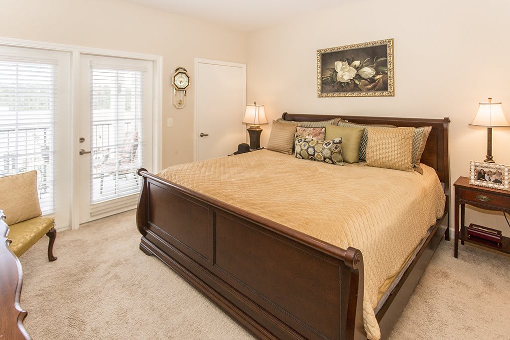 A cozy bedroom with a large wooden bed, decorative pillows, and a lamp on the nightstand.