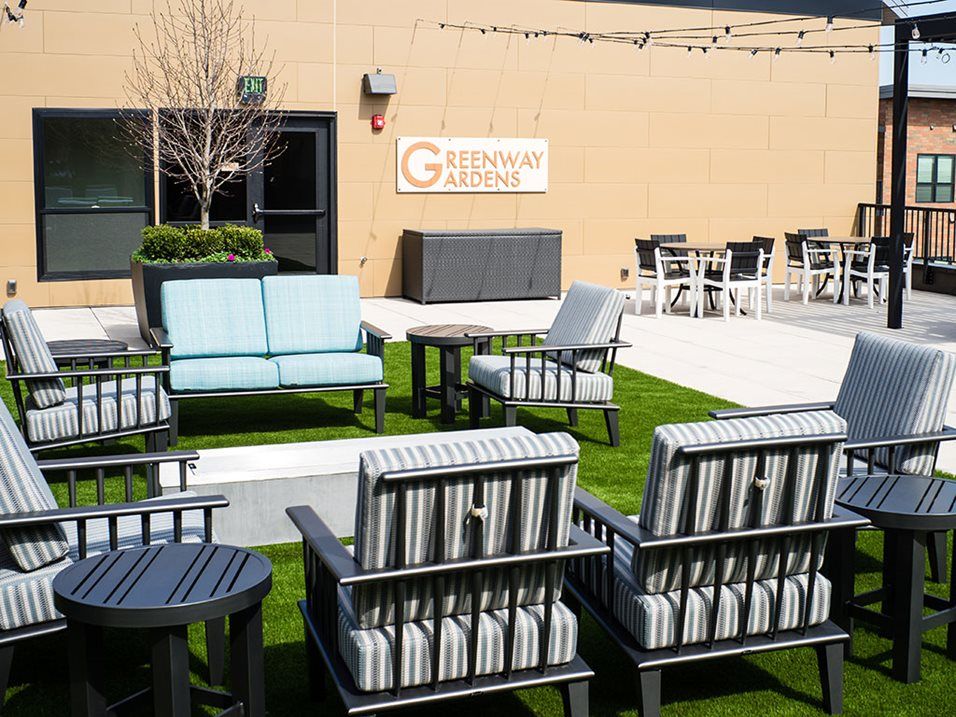 A well-furnished outdoor patio area with chairs and tables arranged on a grassy surface.