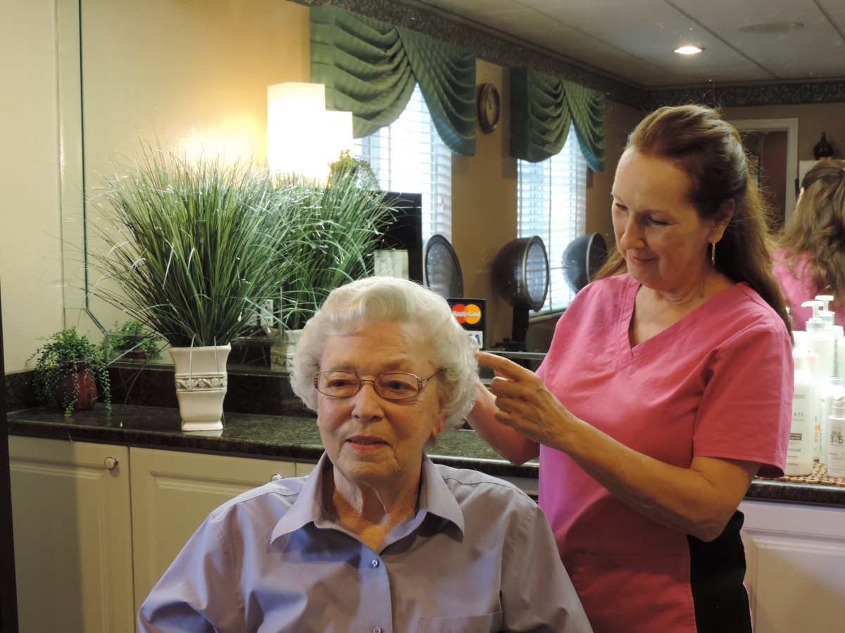 A hairdresser attending to an elderly woman in a salon setting.