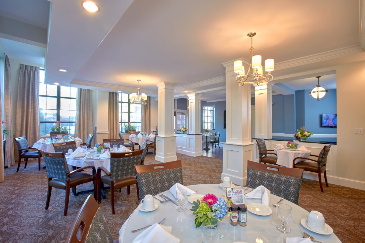 An elegant dining area with neatly arranged tables and chairs, featuring chandeliers and large windows for a sophisticated ambiance.